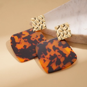 Detail of square vintage amber acrylic earrings with gold hammered textured studs