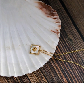 Macro detail of square white mother of pearl necklace with 18k gold rose pendant