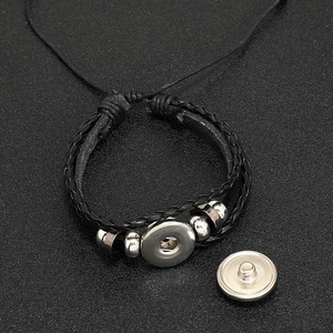 Détail du bracelet en cuir tressé noir avec perles en argent et base de bouton pression