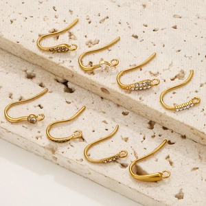 Golden stainless steel earring hooks with zircons on beige travertine stone display