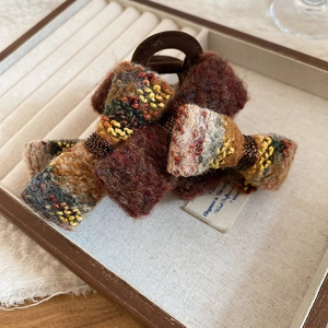 Detail of flocking acrylic bow hair claw with vintage knit texture in autumn colors