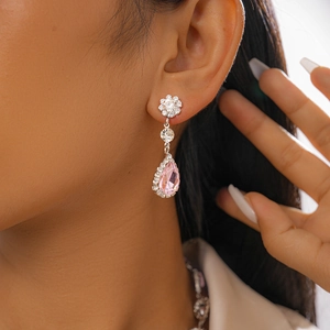 Détail de boucles d'oreilles pendantes roses en forme de goutte portées par un mannequin