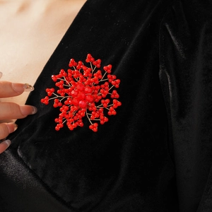 Detail of a handmade red floral beaded brooch pinned on elegant black velvet fabric