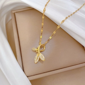 Macro detail of gold leaf pendant with crystal pavé on a white silk background
