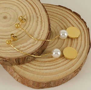 Detail view of gold 18K tassel earrings with pearls on decorative wooden rounds