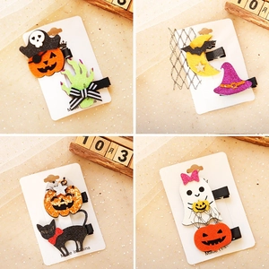 Close-up of glittery Halloween hair clips with pumpkin and ghost motifs on mesh background