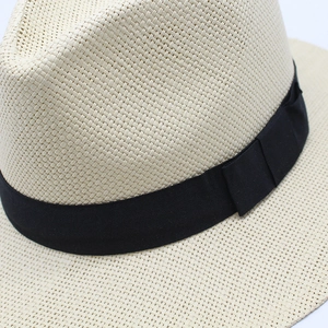 Close-up of beige woven straw fedora hat with a wide black grosgrain ribbon detail