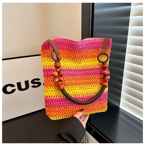 Detail of colorful woven straw bag with brown leather handle and wooden beads decoration