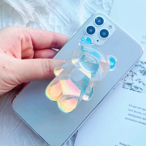 Macro view of a hand holding a phone with a cute iridescent 3D bear pop-up grip