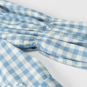 Detailed close-up of blue and white gingham puffed sleeves with elasticated ruffled cuffs
