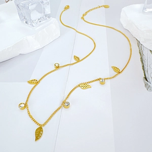 Gold leaf pendant necklace with colorful beads and zircon on a white marble background