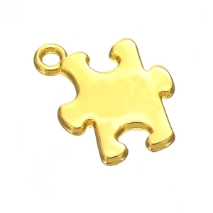 Close-up of a polished gold puzzle piece pendant with a metal ring for DIY jewelry making