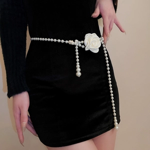 Detail einer eleganten Perlen-Taillenkette mit weißer Rose auf einem schwarzen Kleid