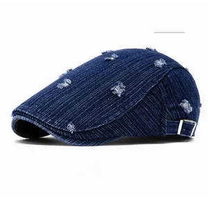 Detail of deep blue distressed denim newsboy cap with vintage metal buckle and frayed edges
