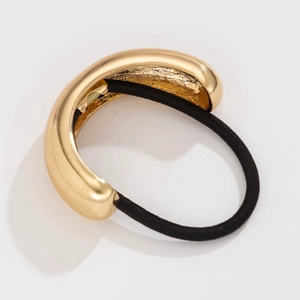 Detail of a sleek golden metallic C-shaped hair tie with high-elastic black cord