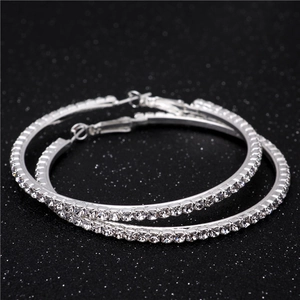 Close-up of large silver hoop earrings encrusted with sparkling clear crystals and zircons