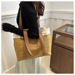 Detail of contrast-color canvas tote bag with leather patch showing large capacity