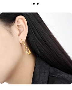 Detailed close-up of irregular textured hollow gold earrings on a female model