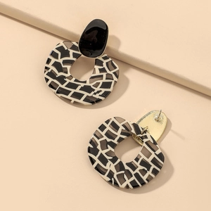 Retro geometric zebra pattern resin earrings with golden pins on a beige display stand