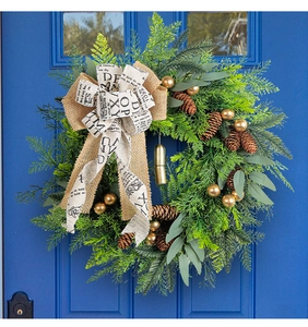 Detail of Christmas wreath with pine cones and burlap bow on a blue door decor