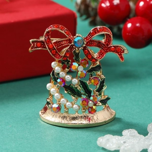 Christmas bell brooch with red bow and colorful rhinestones on a festive background
