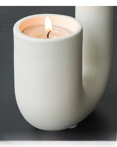 Detail of a minimalist matte white ceramic U-shaped candle holder with a tea light