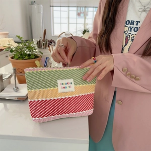 Detailed close-up of a colorful striped woven makeup bag with pink green and yellow patterns