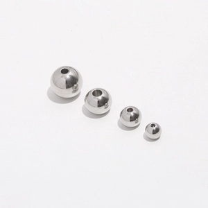 Macro shot of four polished 304 stainless steel round beads with holes for DIY jewelry