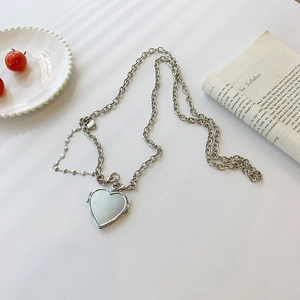 Silver chain necklace with polished heart locket pendant on minimalist aesthetic background