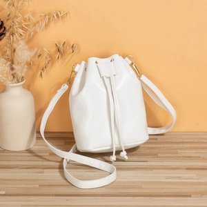 Chic white PU leather bucket bag with gold hardware on a wooden table for daily casual use