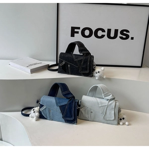 Gros plan de sacs en jean en trois couleurs avec breloques en peluche sur un socle