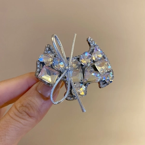 Macro detail of dog-shaped hair clip featuring sparkling rhinestones and silver bow