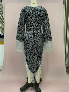 Detail of black dress featuring silver sequin rings and long fringe on sleeves and hem