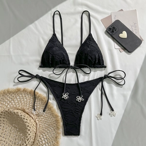 Flat lay of black halter bikini with textured jacquard fabric and floral bead details