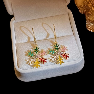 Macro shot of colorful snowflake earrings with enamel finish and zircon in a white jewelry box