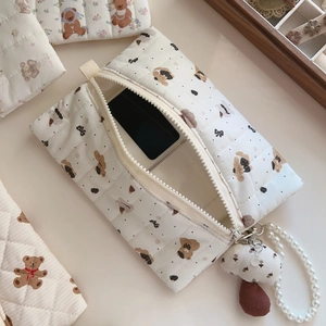 Detail of white quilted cotton pouch with bear patterns and elegant pearl charm chain
