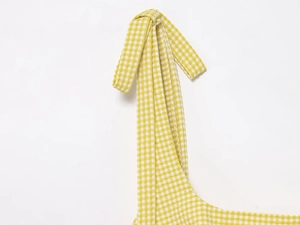 Detail of yellow gingham seersucker fabric featuring adjustable knot shoulder straps