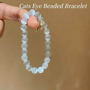 Elegant cat eye stone beaded bracelet with gold bow charm on a minimalist background