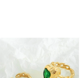Detailed macro view of an 18K gold chain ring featuring a green heart-shaped gemstone