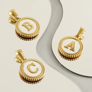 Close-up of 18K gold stainless steel pendants with A, B, C letters and white shell inlay