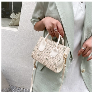 Detail of straw woven bag featuring delicate floral accents and white leather trim finish