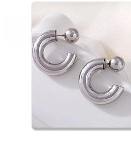Dettaglio di orecchini a cerchio a C color argento con terminale a sfera su supporto