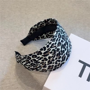 Wide leopard print headband in vintage style, presented on a minimalist fabric background