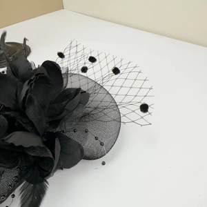 Detail of vintage black fascinator hat with 3D floral petals, mesh veil and feathers