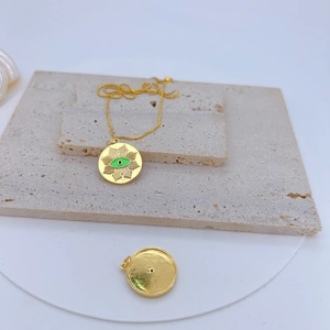 Detail of gold-plated sunburst devil eye pendant with green zircon and enamel inlay