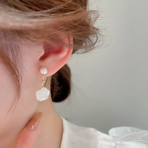 Close-up of elegant white flower drop earrings with pearls on a model