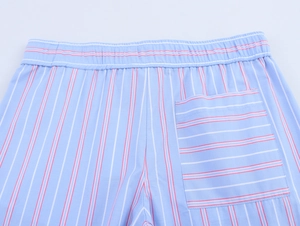 Close-up of elastic waistband and striped back pocket on blue cotton trousers