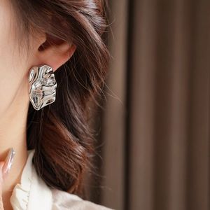 Detailed close-up of model wearing silver irregular earrings with liquid metal texture