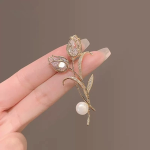 Detailed close-up of golden tulip brooch with faux diamonds and a pearl accent