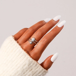 Détail d'une bague double argentée avec breloques soleil et étoile sur main